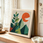 Green leaves and mountains punch needle artwork displayed on a table