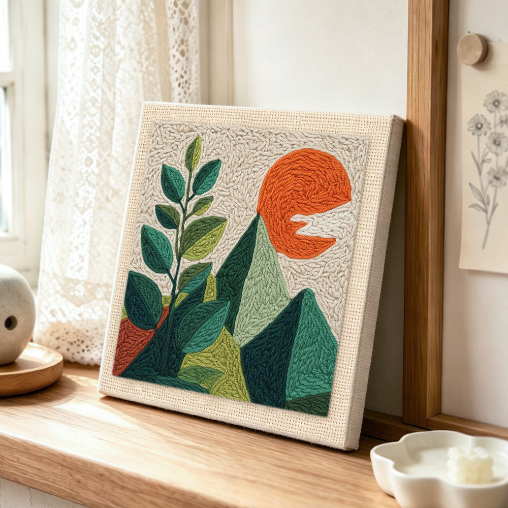 Green leaves and mountains punch needle artwork displayed on a table