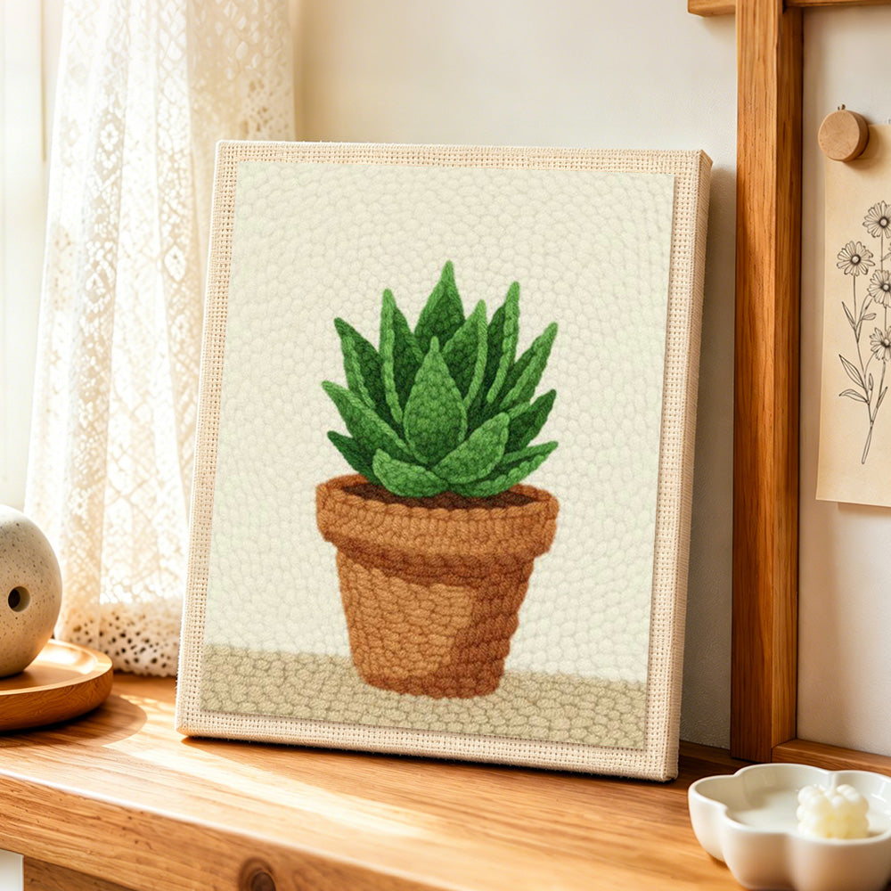 Green succulent in terracotta pot punch needle artwork displayed on a table
