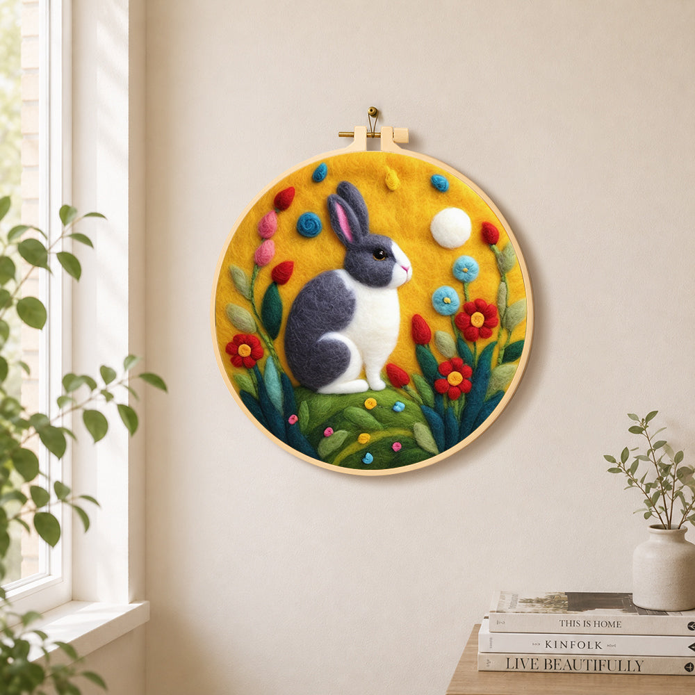 Grey and white rabbit among flowers needle felt wall art displayed in a bright home interior