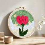 Growing red flower punch needle artwork displayed on a table