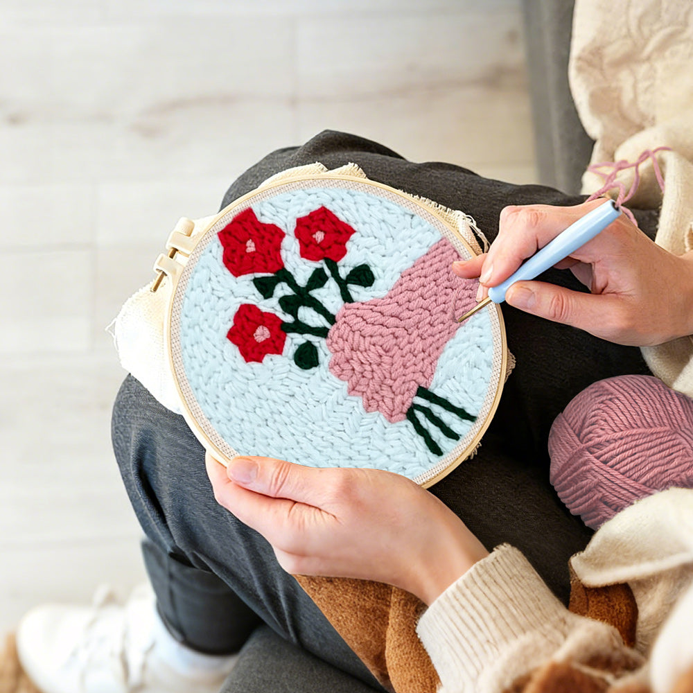 Creating handmade hand holding red flowers punch needle artwork