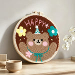 Happy bear with flowers punch needle artwork displayed on a table