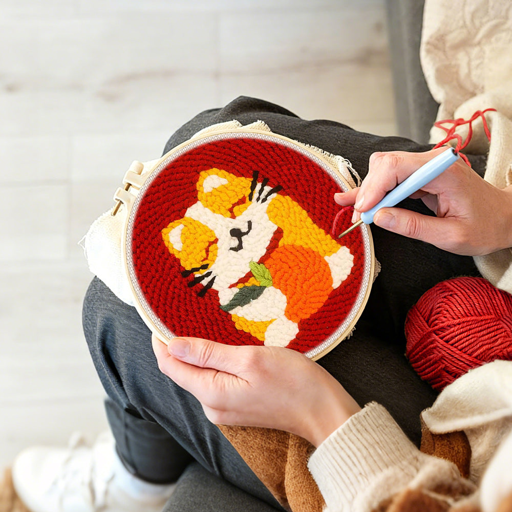 Creating handmade happy cat holding an orange punch needle artwork