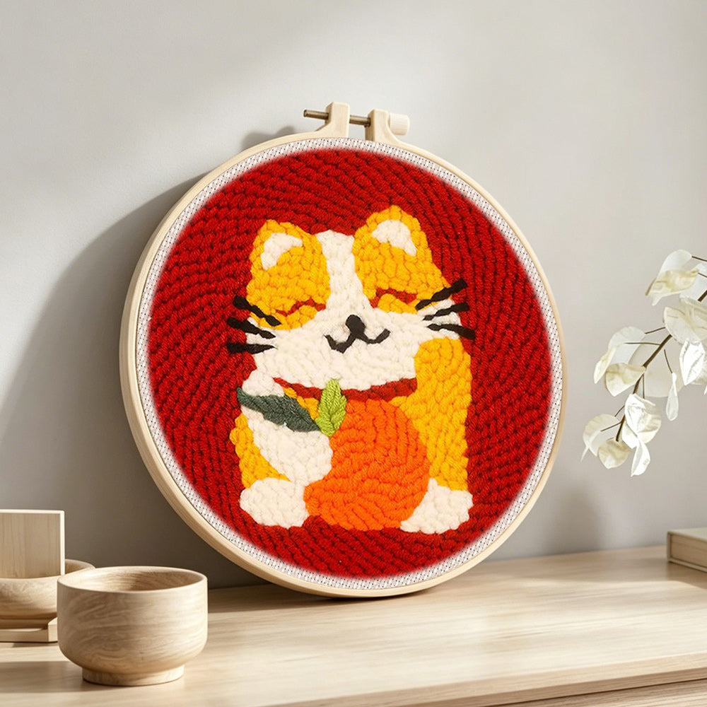 Happy cat holding an orange punch needle artwork displayed on a table