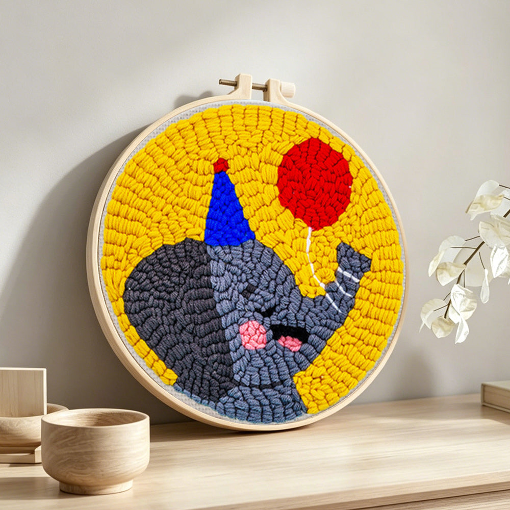 Happy elephant with a red balloon punch needle artwork displayed on a table