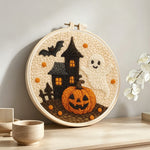 Haunted house, ghost and pumpkin punch needle artwork displayed on a table