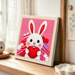 Heart-holding bunny punch needle artwork displayed on a table