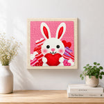 Finished heart-holding bunny artwork displayed on a wall