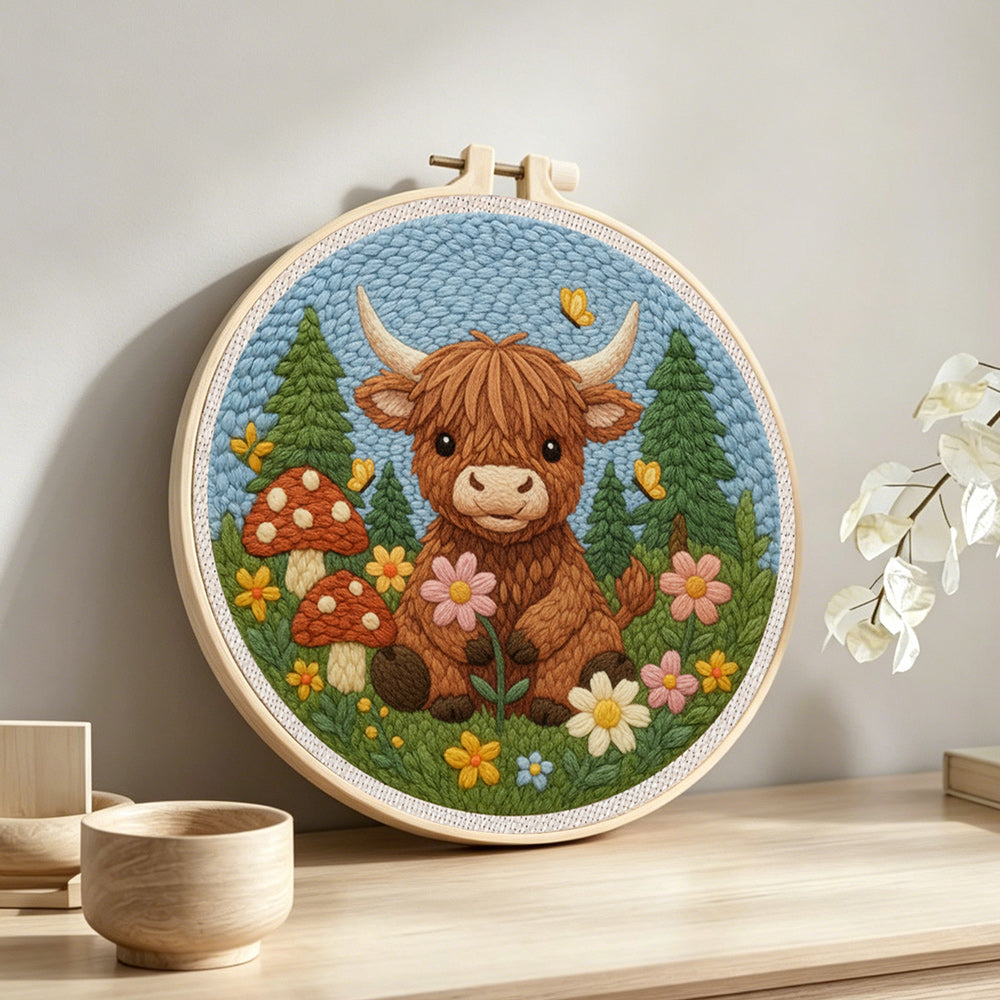 Highland cow and mushrooms in spring punch needle artwork displayed on a table