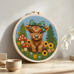 Highland cow and mushrooms on the green grass punch needle artwork displayed on a table