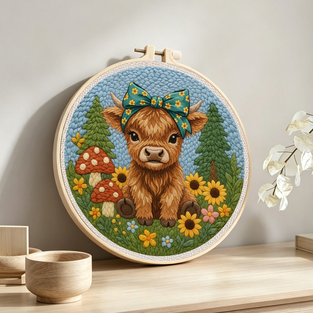 Highland cow and mushrooms on the green grass punch needle artwork displayed on a table