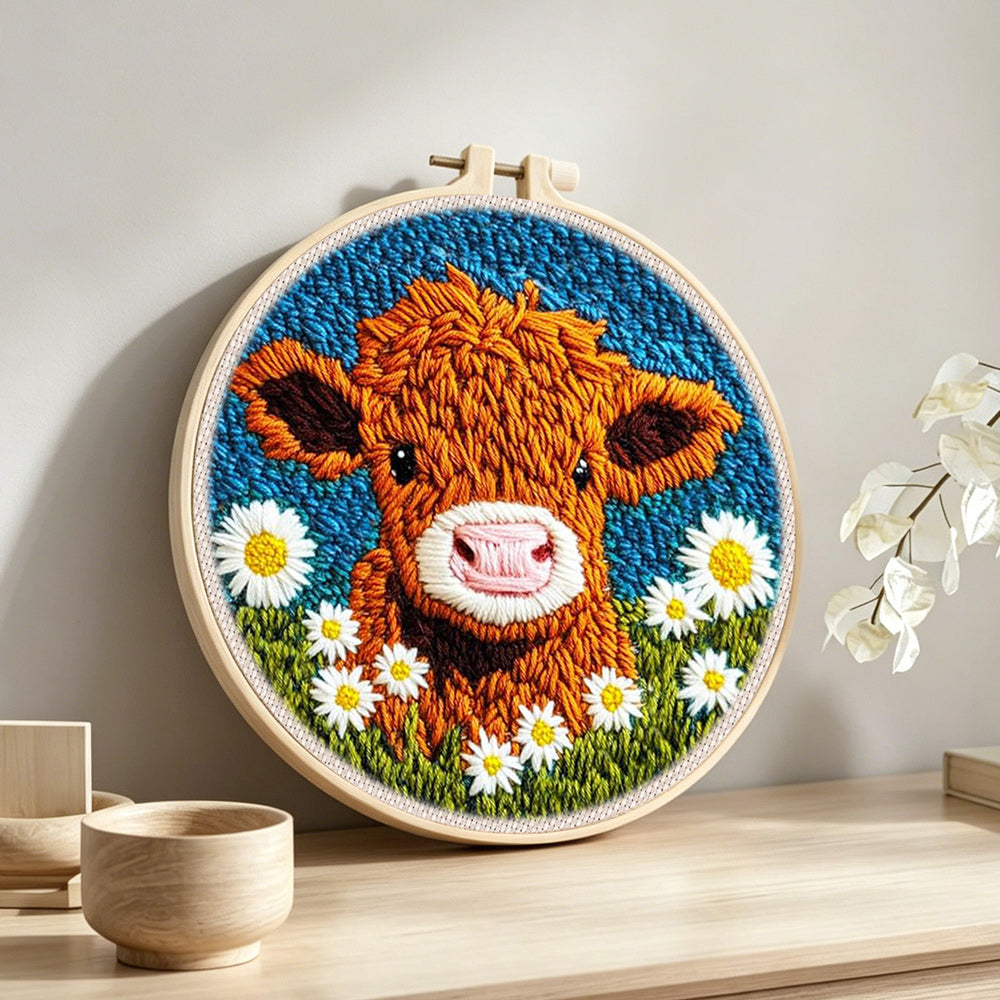 Highland cow and white daisies punch needle artwork displayed on a table