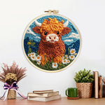 Finished highland cow, mountains and daisies artwork displayed on a wall
