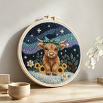 Highland cow, mountains and sunflowers punch needle artwork displayed on a table