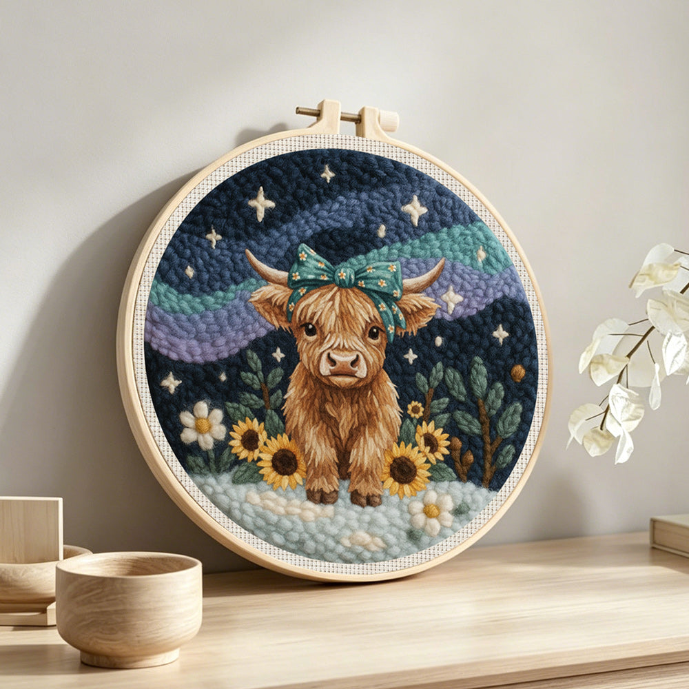 Highland cow, mountains and sunflowers punch needle artwork displayed on a table