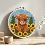 Highland cow surrounded by sunflowers punch needle artwork displayed on a table