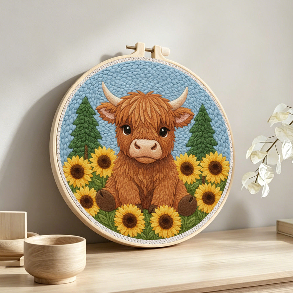 Highland cow surrounded by sunflowers punch needle artwork displayed on a table