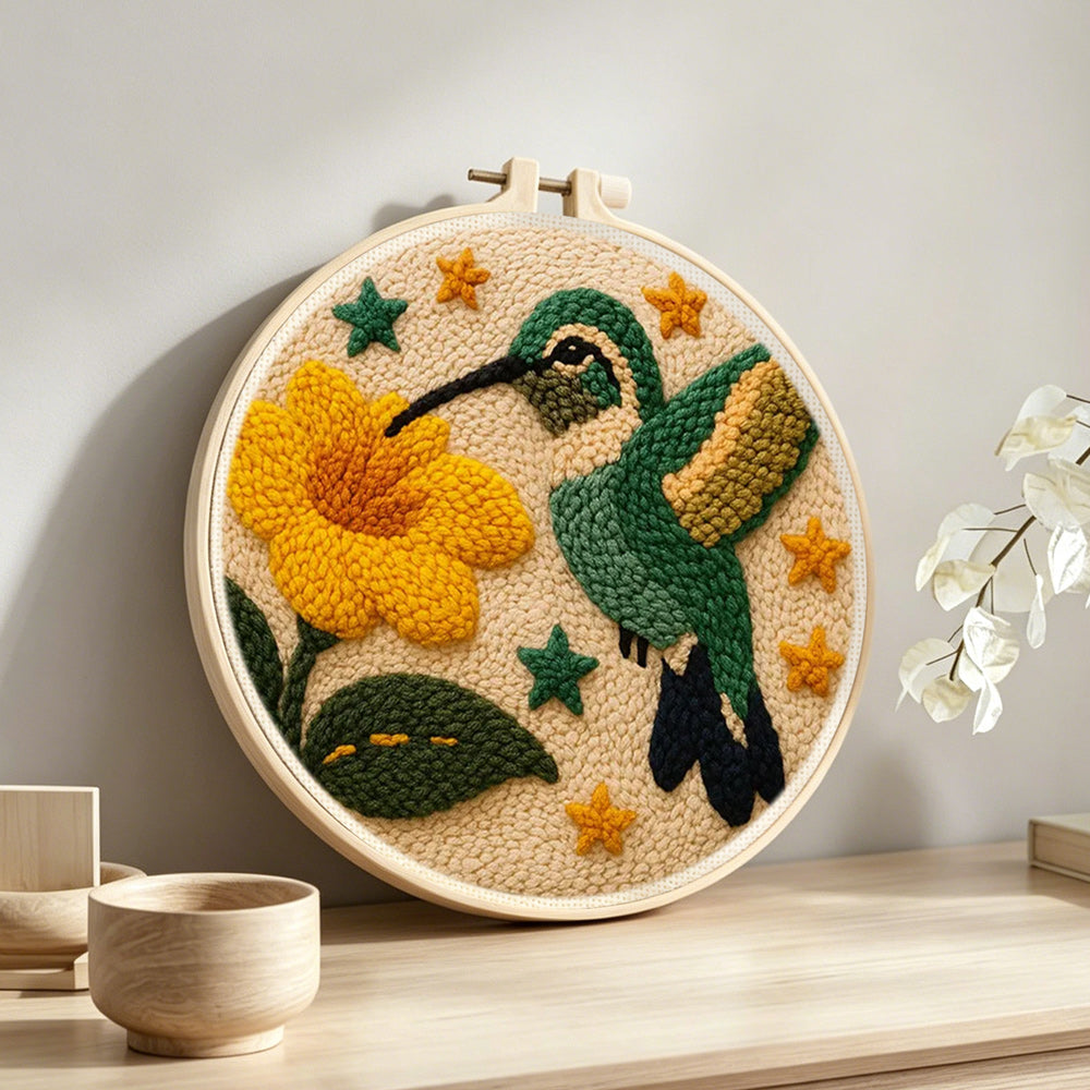 Hummingbird and flower punch needle artwork displayed on a table