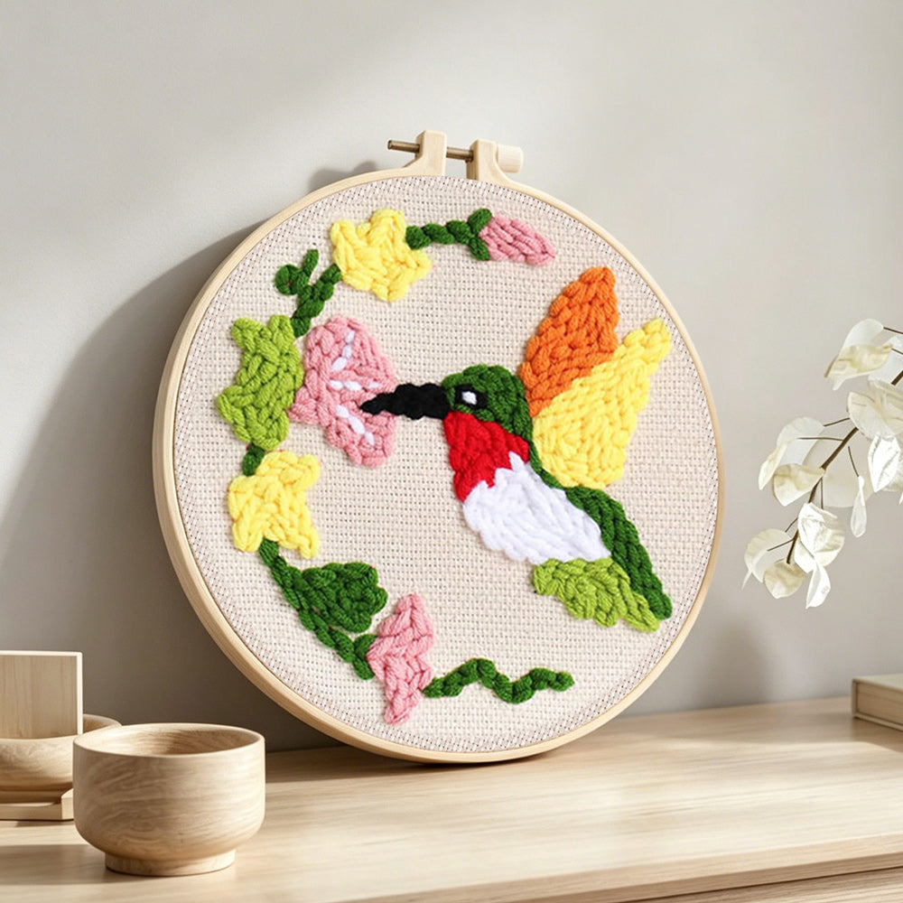 Hummingbird and flowers punch needle artwork displayed on a table
