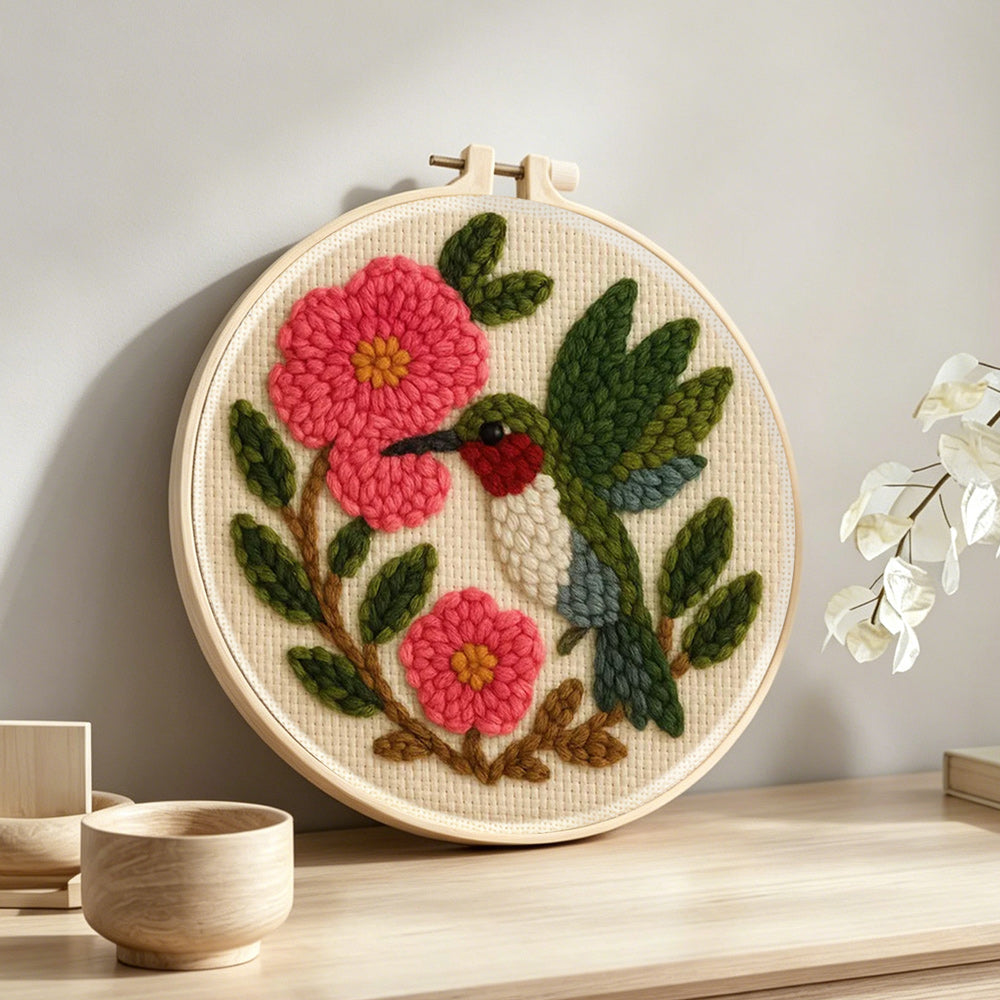 Hummingbird and pink flowers punch needle artwork displayed on a table