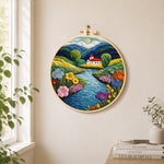 Idyllic mountain village and river needle felt wall art displayed in a bright home interior