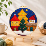 Finished illuminated christmas village needle felting displayed on a wooden easel