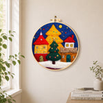 Illuminated christmas village needle felt wall art displayed in a bright home interior