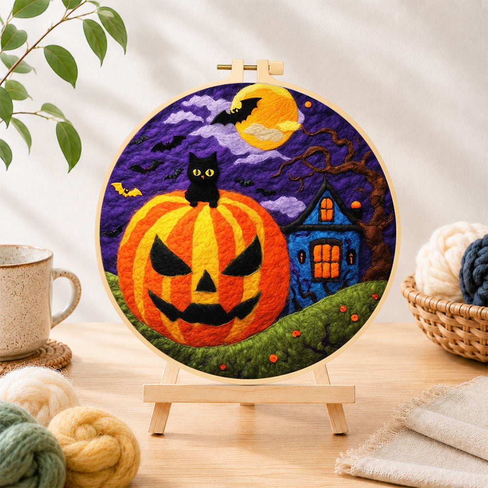 Finished jack-o'-lantern and haunted house needle felting displayed on a wooden easel