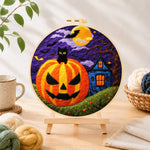 Finished jack-o'-lantern and haunted house needle felting displayed on a wooden easel