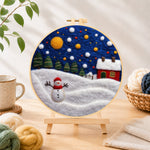 Finished jolly snowman and red winter cottage needle felting displayed on a wooden easel