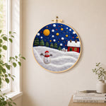 Jolly snowman and red winter cottage needle felt wall art displayed in a bright home interior