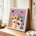 Kittens holding hearts punch needle artwork displayed on a table