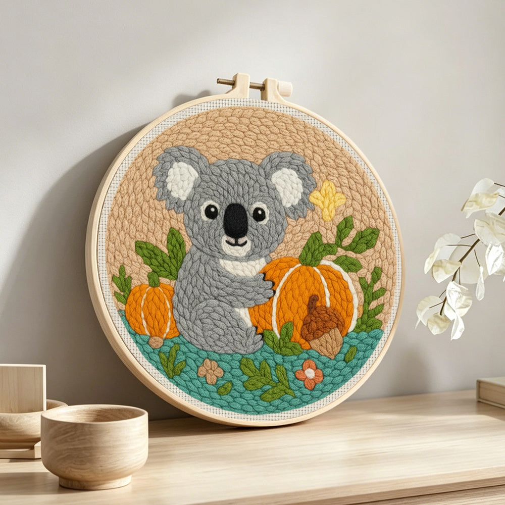 Koala and pumpkins in autumn punch needle artwork displayed on a table