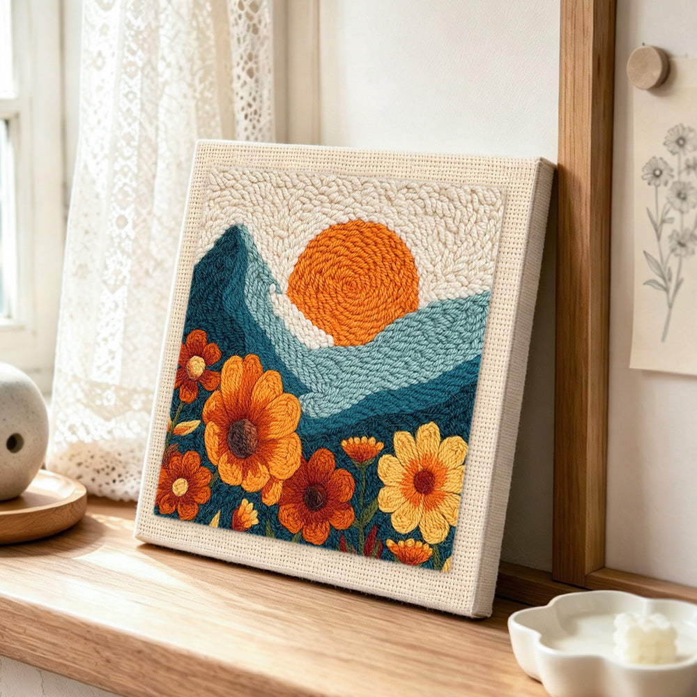 Large marigold flowers and setting sun punch needle artwork displayed on a table
