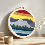 Layered mountain landscape punch needle artwork displayed on a table