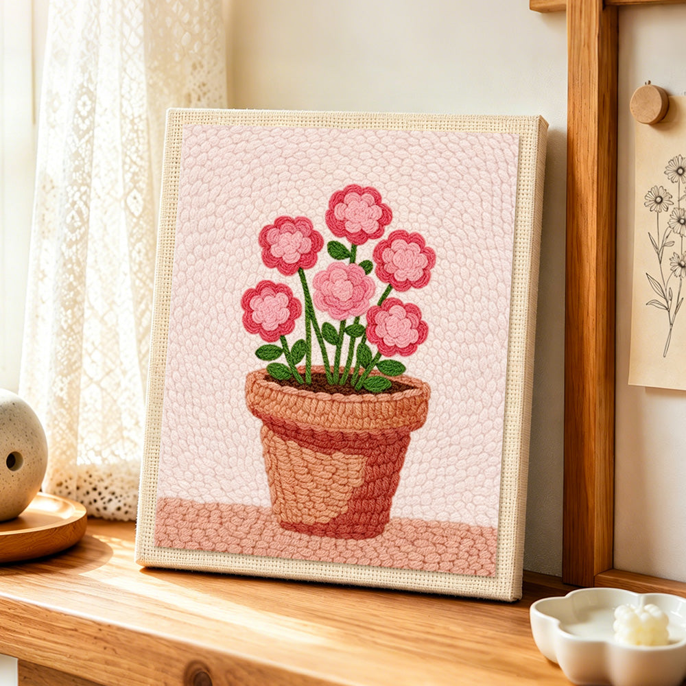 Layered pink flowers in pot punch needle artwork displayed on a table