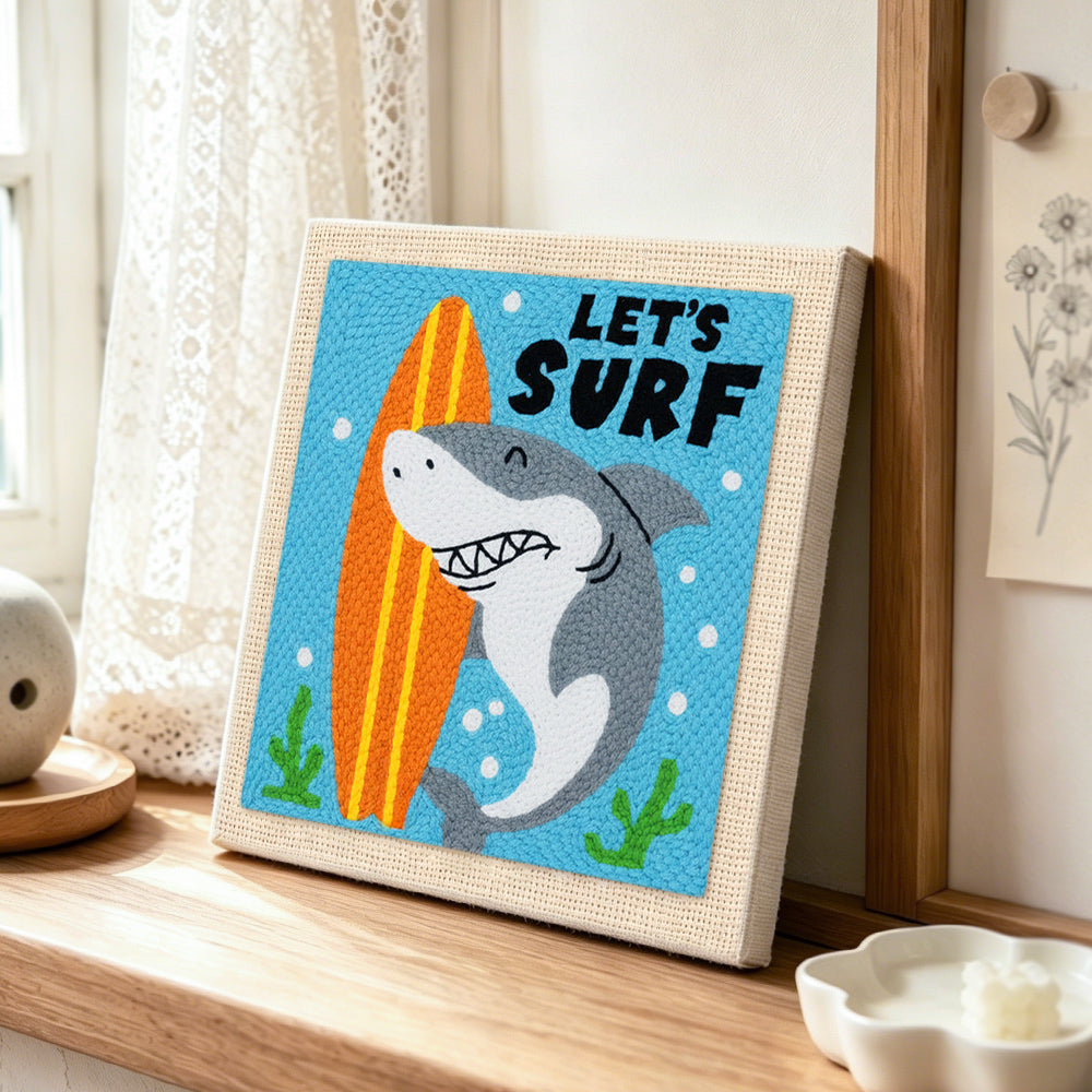 "LET'S SURF" shark with surfboard punch needle artwork displayed on a table