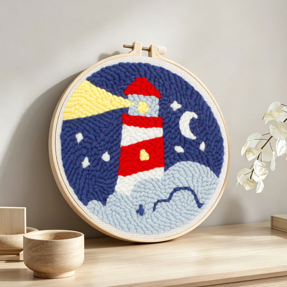 Lighthouse at night punch needle artwork displayed on a table