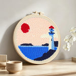 Lighthouse by the sea punch needle artwork displayed on a table