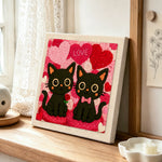 "LOVE" black cat couple with rose punch needle artwork displayed on a table