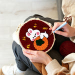 Creating handmade lucky bunny hugging an orange punch needle artwork