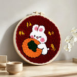 Lucky bunny hugging an orange punch needle artwork displayed on a table