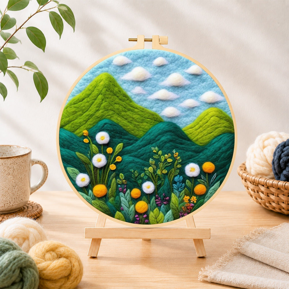 Finished lush green mountains and wildflowers needle felting displayed on a wooden easel