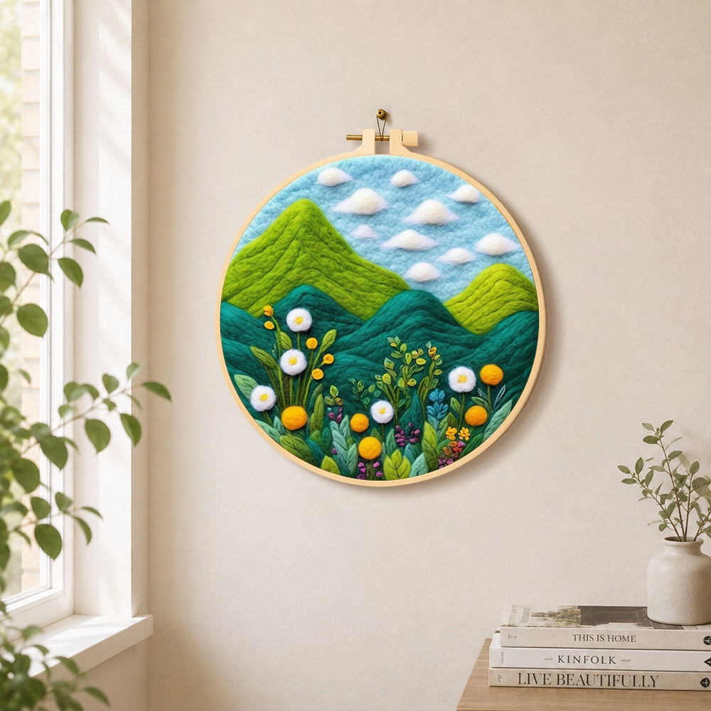 Lush green mountains and wildflowers needle felt wall art displayed in a bright home interior