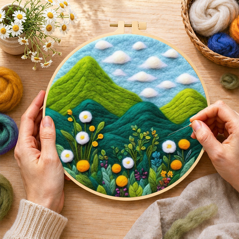 Creating the lush green mountains and wildflowers wool painting by hand with a felting needle