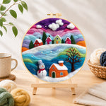 Finished magical rainbow snowy village at christmas needle felting displayed on a wooden easel