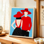 Matching red hats couple punch needle artwork displayed on a table