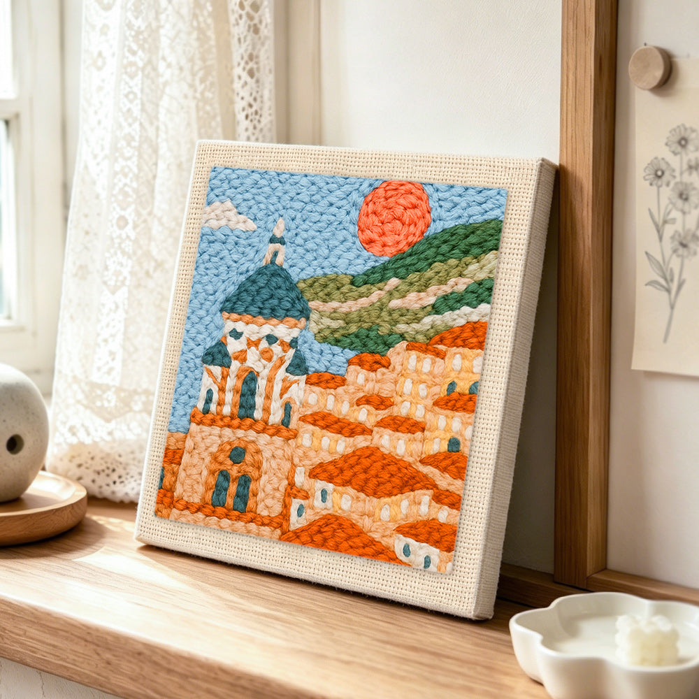 Mediterranean coastal town punch needle artwork displayed on a table