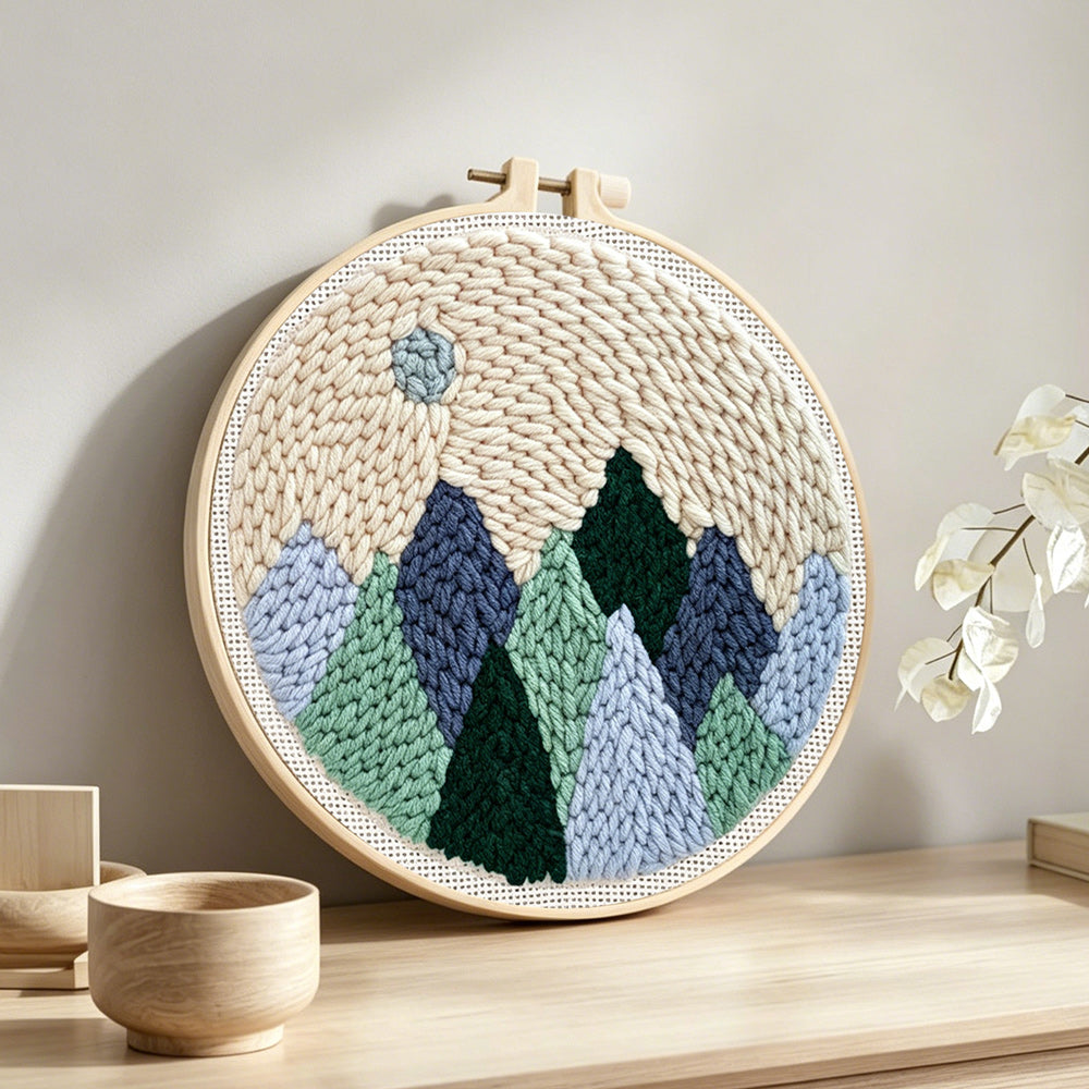 Minimal mountain landscape with moon punch needle artwork displayed on a table